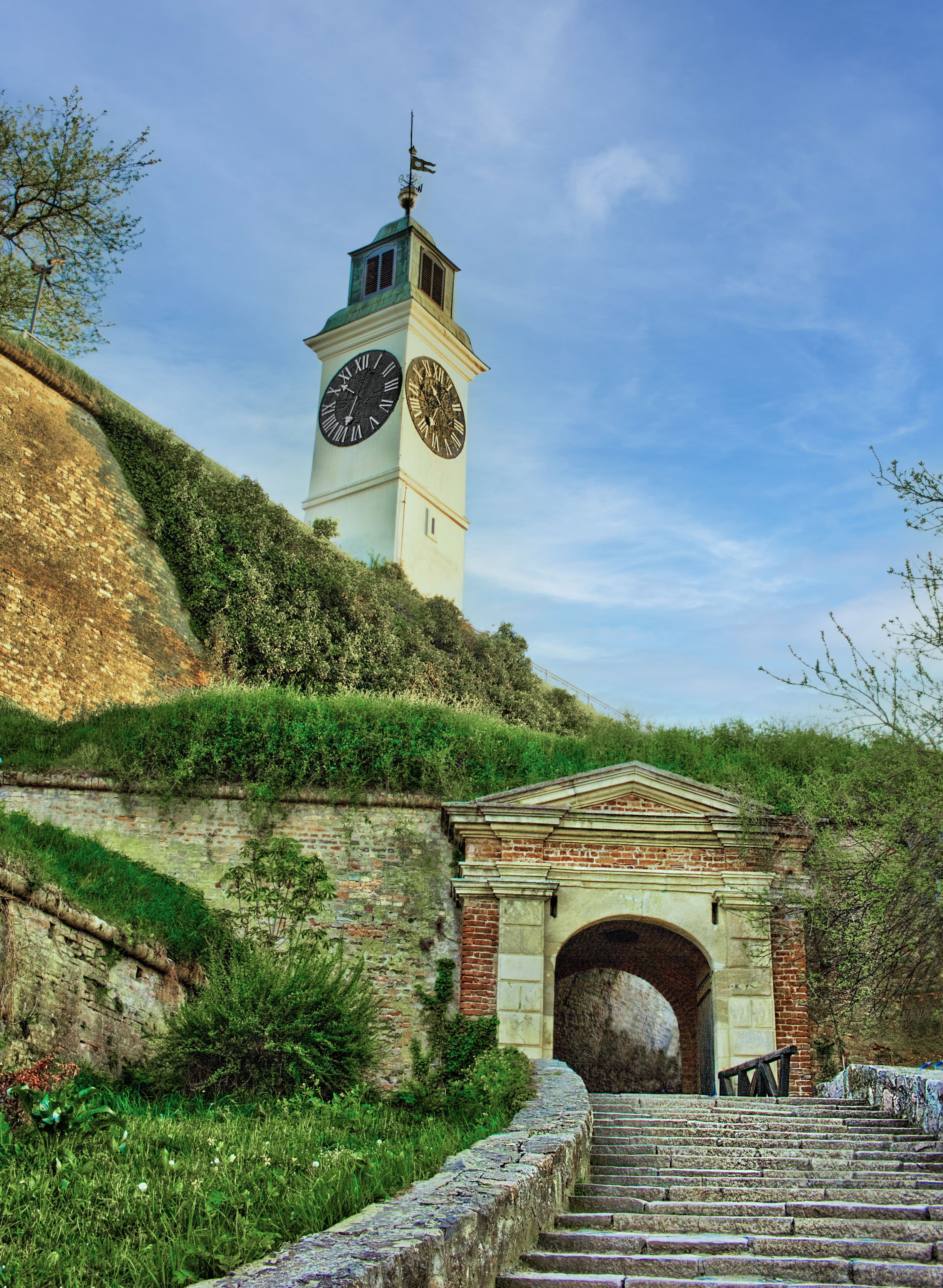 The clock tower above a gate and stone stairs at Petrovaradin Fortress